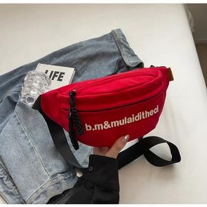 Detail of red canvas crossbody bag featuring white letter embroidery and black adjustable strap