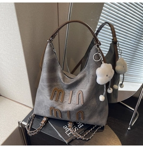 Gray Hobo bag detail with brown leather letters, silver chain, and cloud charm