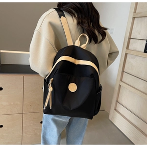 Detail view of stylish black nylon backpack with beige straps on a female model