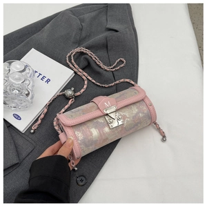 Pink tweed cylinder bag with silver chain strap and M buckle shown in a lifestyle setting