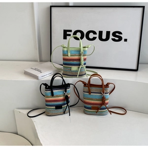 Detail view of colorful striped straw mini tote bags with tassels and long shoulder straps