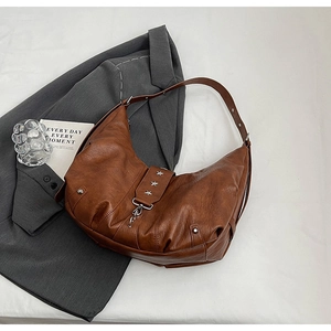 Détail du sac croissant marron vintage avec rivets étoiles argentés et texture en cuir