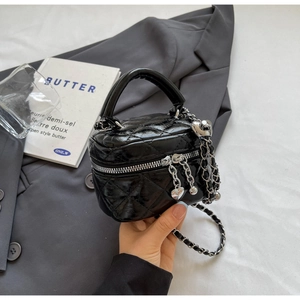 Close-up of black quilted mini vanity bag with silver chain and heart charm details