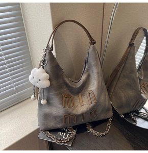 Detail of grey tote bag with min min leather patch and white plush cloud charm