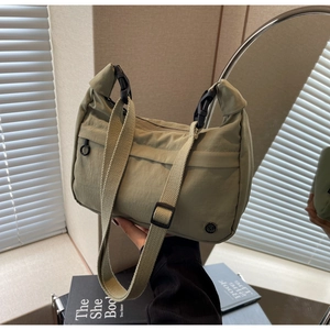 Gros plan sur un sac bandoulière en nylon vert olive avec sangle réglable et logo