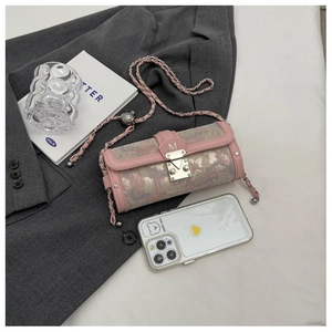 Detail of pink cylinder bag with M buckle and leather metal chain over business suit