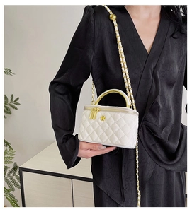 Detail of white quilted leather mini vanity bag with gold camellia logo and chain strap