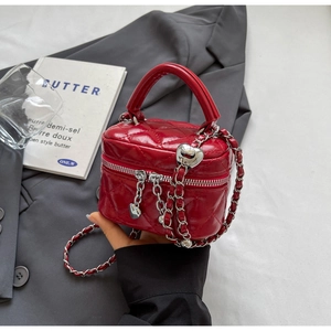 Detail of red quilted mini box bag with silver heart charms and chain strap