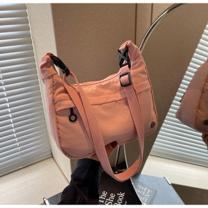 Détail du sac dumpling en nylon rose avec boucle noire et logo métallique rond