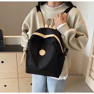 Close-up of lightweight black nylon backpack with beige leather straps and circular logo