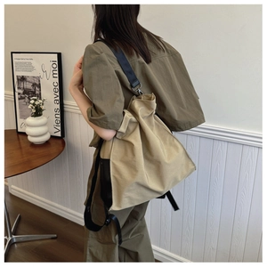 Detailed side view of khaki canvas drawstring tote bag with black adjustable straps