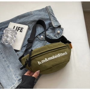 Detail of army green nylon chest bag with white embroidery on casual denim background