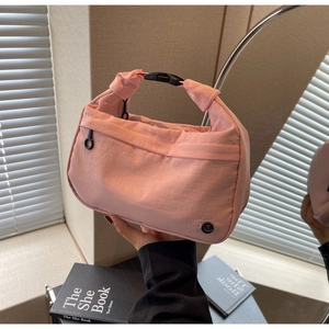 Détail du sac à main en nylon rose avec logo métallique M et boucle en plastique noir