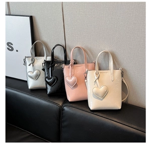Detail of four mini straw-style heart charm tote bags in silver, black, pink, and cream