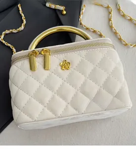 Close-up of beige quilted box bag with golden metal handle and camellia emblem decoration