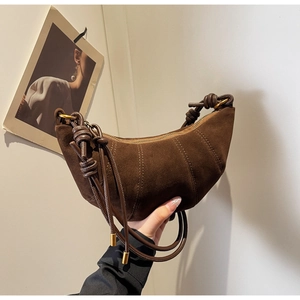 Detail of the dark brown suede dumpling bag featuring visible stitching and a side knot strap