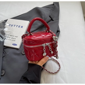 Detail of red quilted vanity bag with heart pendant and silver chain strap