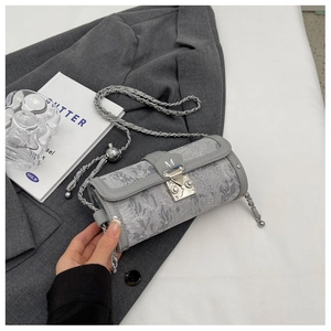 Close-up of gray jacquard cylinder bag with silver M buckle and chain strap