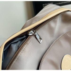 Close-up of smooth nylon fabric and silver metal zipper on stylish taupe backpack
