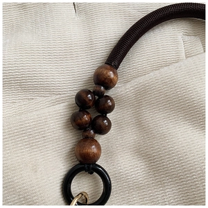 Détail macro de perles en bois poli marron foncé et corde tissée avec crochet doré