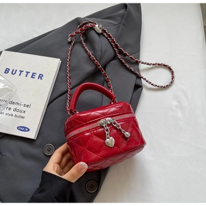 Detailed close-up of red quilted mini box bag featuring heart-shaped zippers and silver chain
