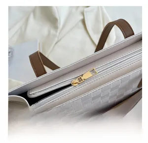 Detailed close-up of smooth gold metal zipper and checkered texture on a tote bag