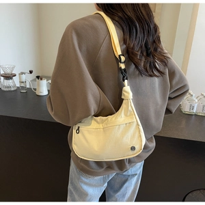 Détail du sac croissant en nylon crème avec bandoulière large et boucle de serrage