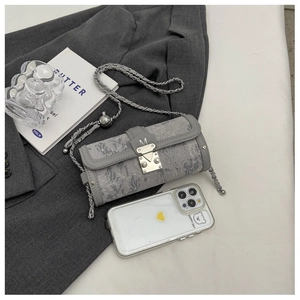 Detailed view of gray cylindrical chain bag shown with iPhone for size comparison