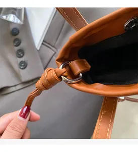Close-up of brown leather bag strap with yellow stitching and silver ring hardware detail