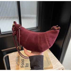Detail of burgundy suede croissant bag showing premium stitching and crescent moon shape