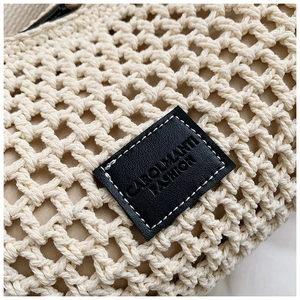 Close-up of cream crochet knit bag featuring honeycomb mesh texture and black leather label