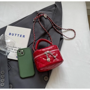 Macro shot of red quilted mini box bag with heart pendant on a grey suit background