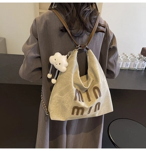 Detail of khaki canvas tote bag with leather straps and cloud charm shown on model