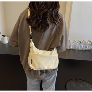 Détail du sac bandoulière croissant crème avec sangle réglable porté par un mannequin