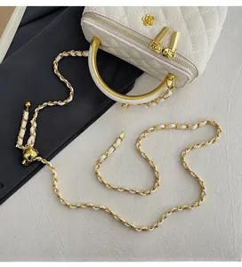 Detail of white quilted vanity bag with gold hardware and circular metal handle