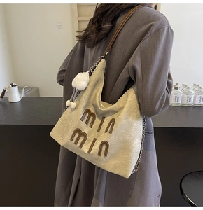 Detail view of large canvas tote bag with brown straps and white pompom on female model