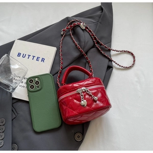 Detail of red quilted mini bag with silver heart charm and leather chain strap