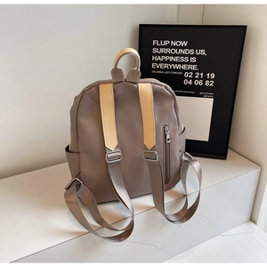 Detail view of the taupe PU leather backpack featuring back anti-theft zipper and side pockets
