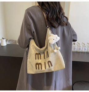 Detail of khaki canvas tote bag with MIn MIn embroidery and cloud plush charm
