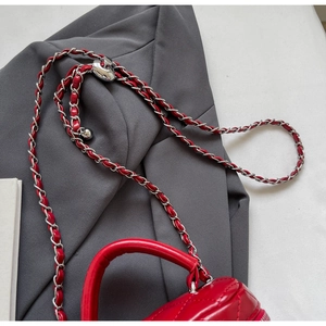 Close-up of red quilted leather texture and silver chain strap with metal adjustment ball