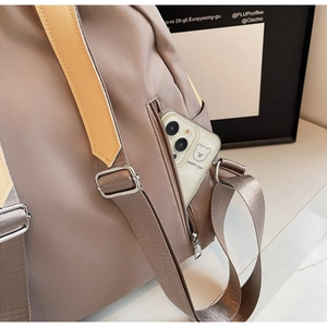 Detail view of water-resistant nylon backpack featuring a side zipper pocket for smartphone