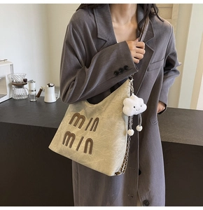 Detail of light khaki hobo bag with MIN MIN lettering and a cute white cloud pendant