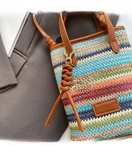 Detail of colorful woven straw bag with premium leather handles and brand logo patch