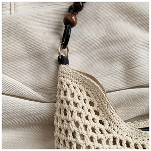 Détail du sac cabas en paille tissée avec perles en bois brun et boucle en métal doré