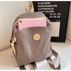 Detail view of khaki nylon backpack front pocket showing space for a pink tablet device