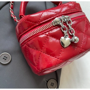 Detail of red quilted mini box bag with double zippers and metallic heart charms