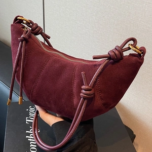 Burgundy suede croissant crossbody bag with knot shoulder strap and pleated stitch design