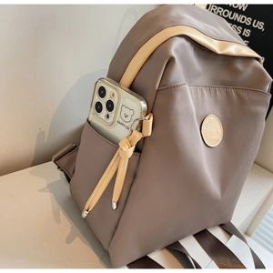 Detail of a minimalist brown backpack side pocket with a smartphone inside for storage
