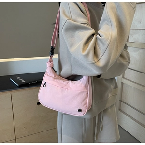 Vue détaillée d'un sac bandoulière en nylon rose en forme de croissant avec sangle