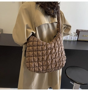 Detail of coffee brown quilted cloud hobo bag showing the puffy texture on models shoulder